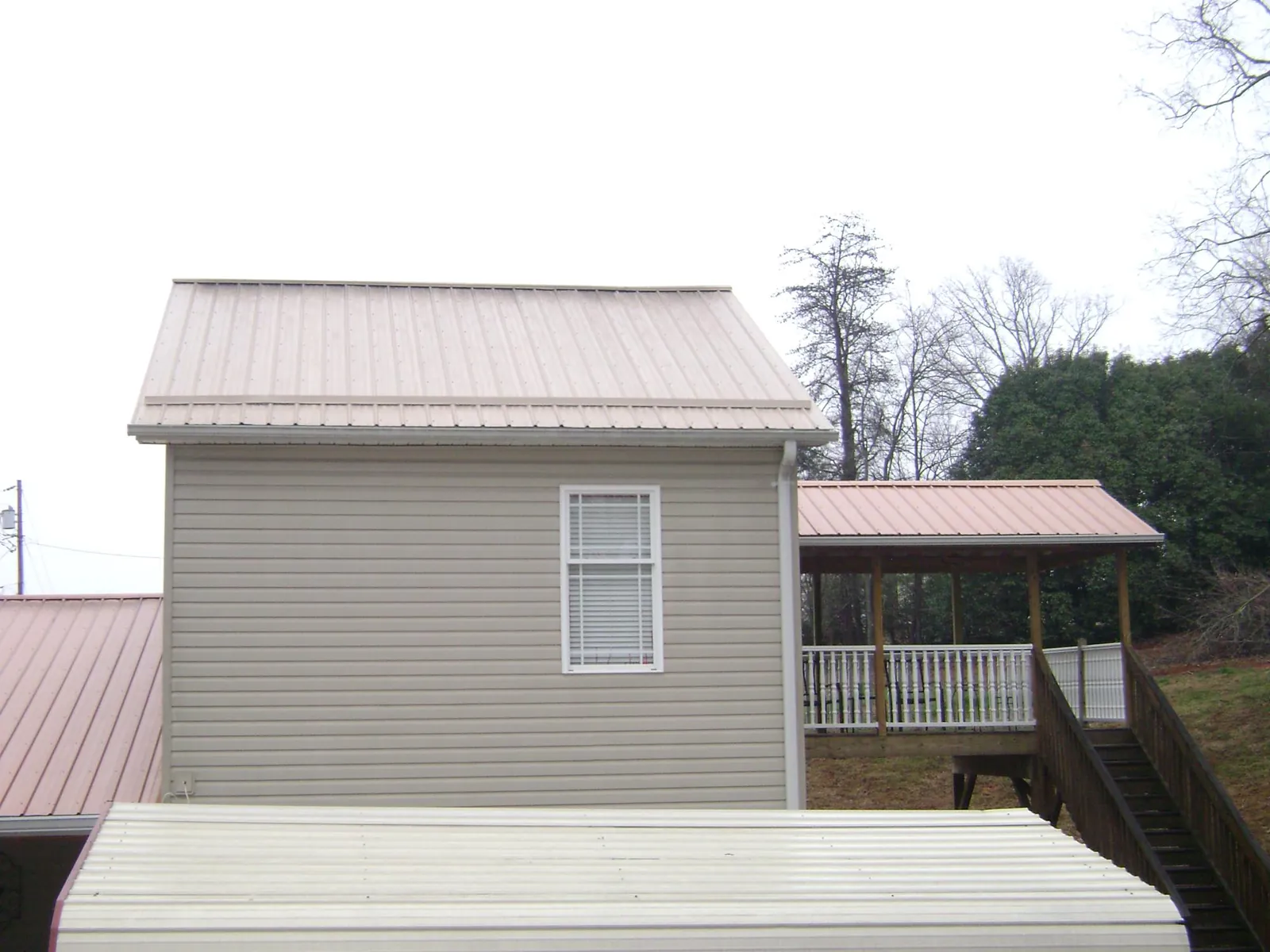Tan metal roofs on a two story addition and attached porch, from a Roof Replacement job in Vardaman